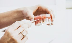 person wearing silver-colored ring while holding denture